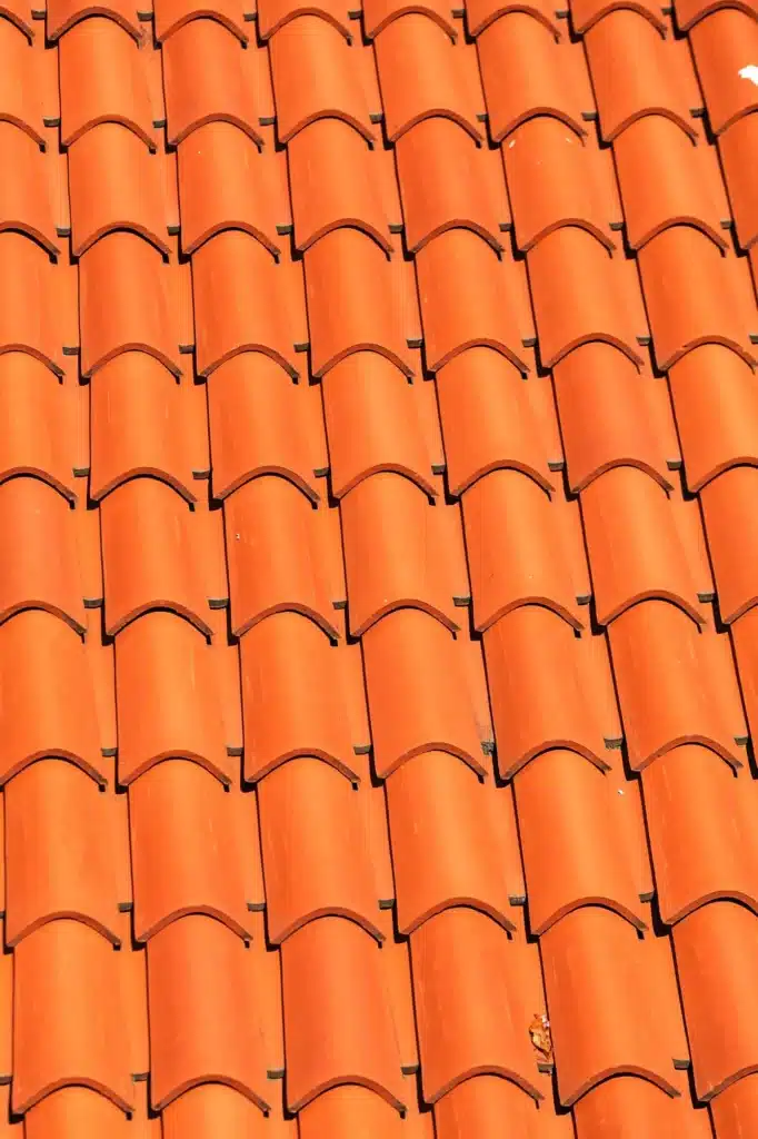 Tuiles canal terracotta : motif de toiture orange vibrant. Motif texturé de tuiles de toiture canal en terre cuite orange vif. L'alignement serré des tuiles crée des ombres profondes.